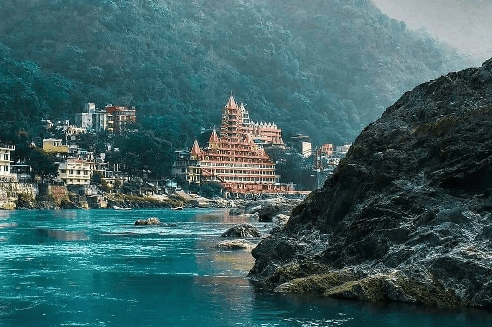Top 12 Beautiful Hill Stations & Spiritual Destinations in Uttarakhand Rishikesh having River Ganga and a temple