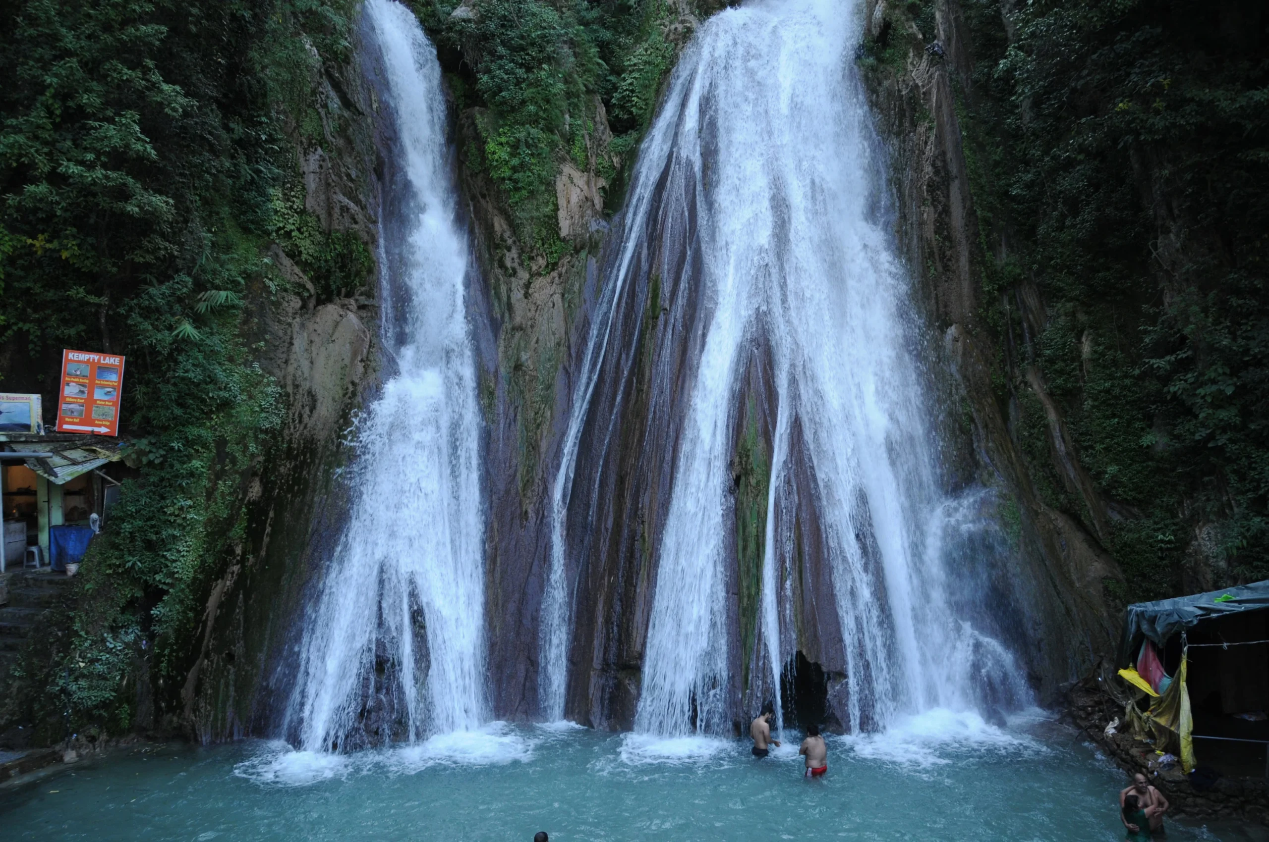 Top 12 Beautiful Hill Stations & Spiritual Destinations in Uttarakhand Kampati fall Mussoorie people swimming in a pool of water with Kempty Falls in the background